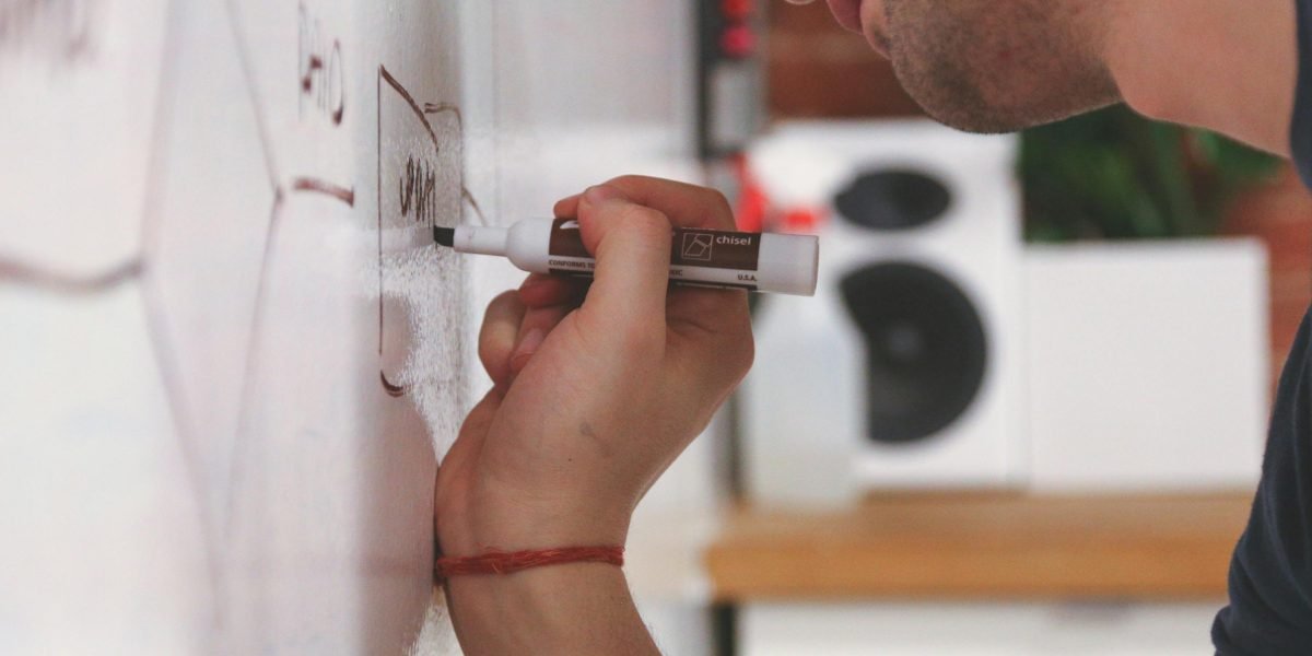 A person actively working through ideas on a whiteboard, symbolizing the process of gaining new vocabulary and understanding.