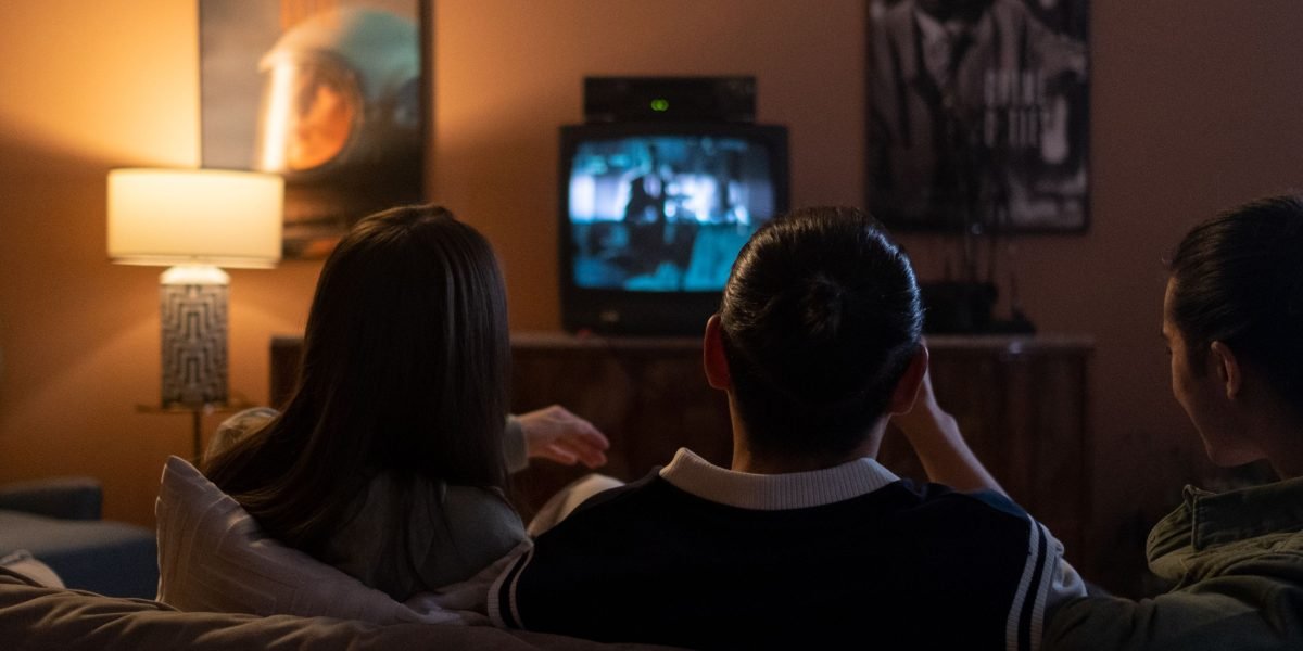 Friends watching and reacting to a science fiction or fantasy movie, finding humor in the unfamiliar.
